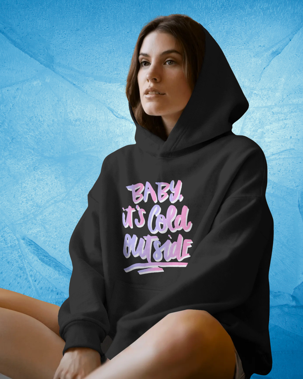 Person wearing a black hoodie with pink text against a blue textured background