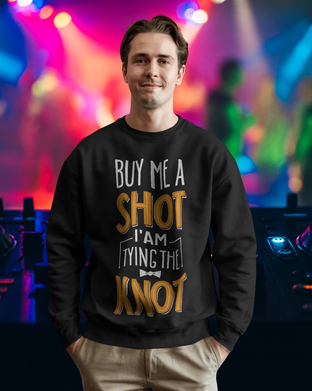 Man wearing a black sweatshirt with a humorous print in front of colorful stage lights