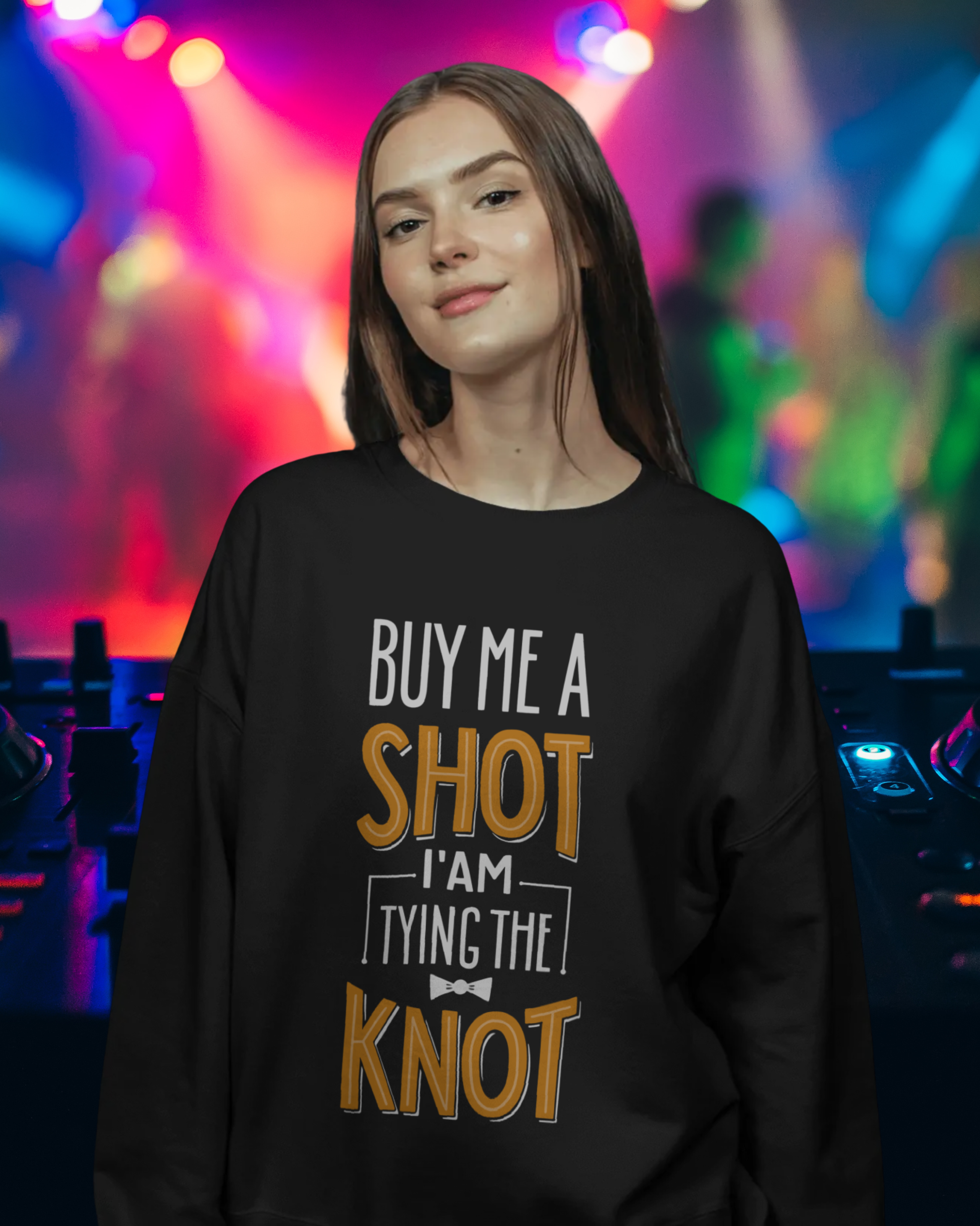 Person wearing a black sweatshirt with a humorous text design in front of colorful stage lights