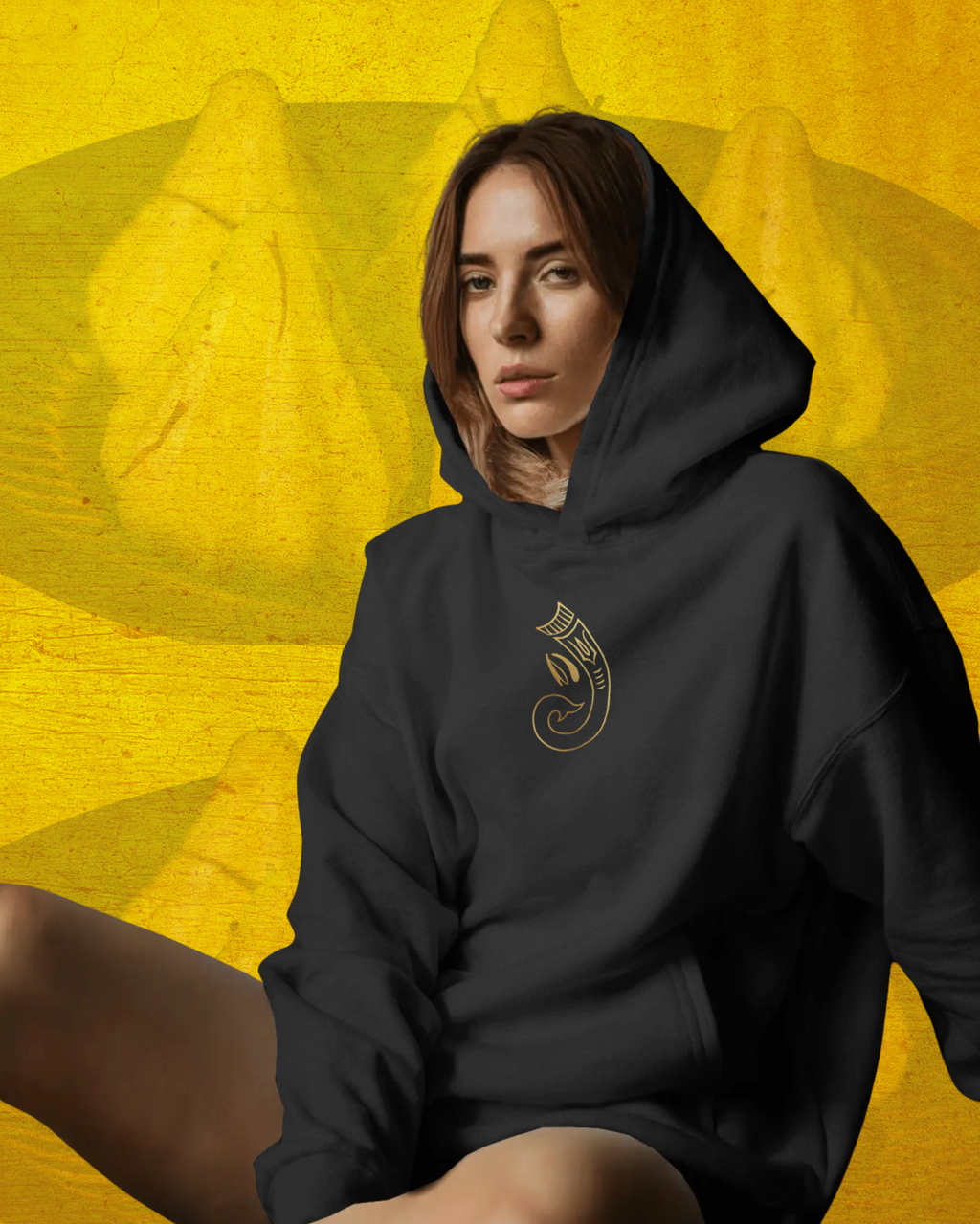 Person wearing a black hoodie with a logo on a yellow background