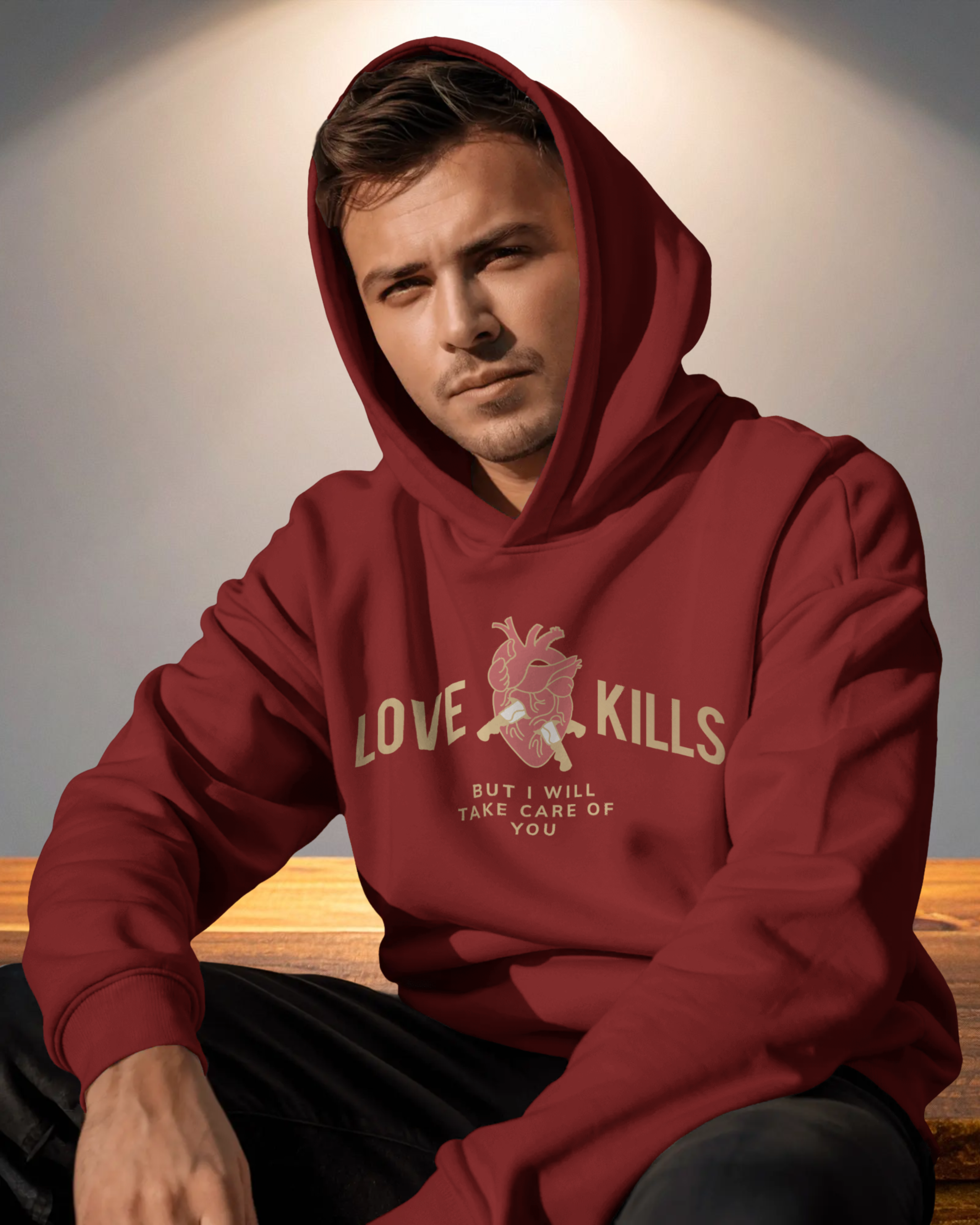 Man wearing a red hoodie with text sitting on a wooden surface