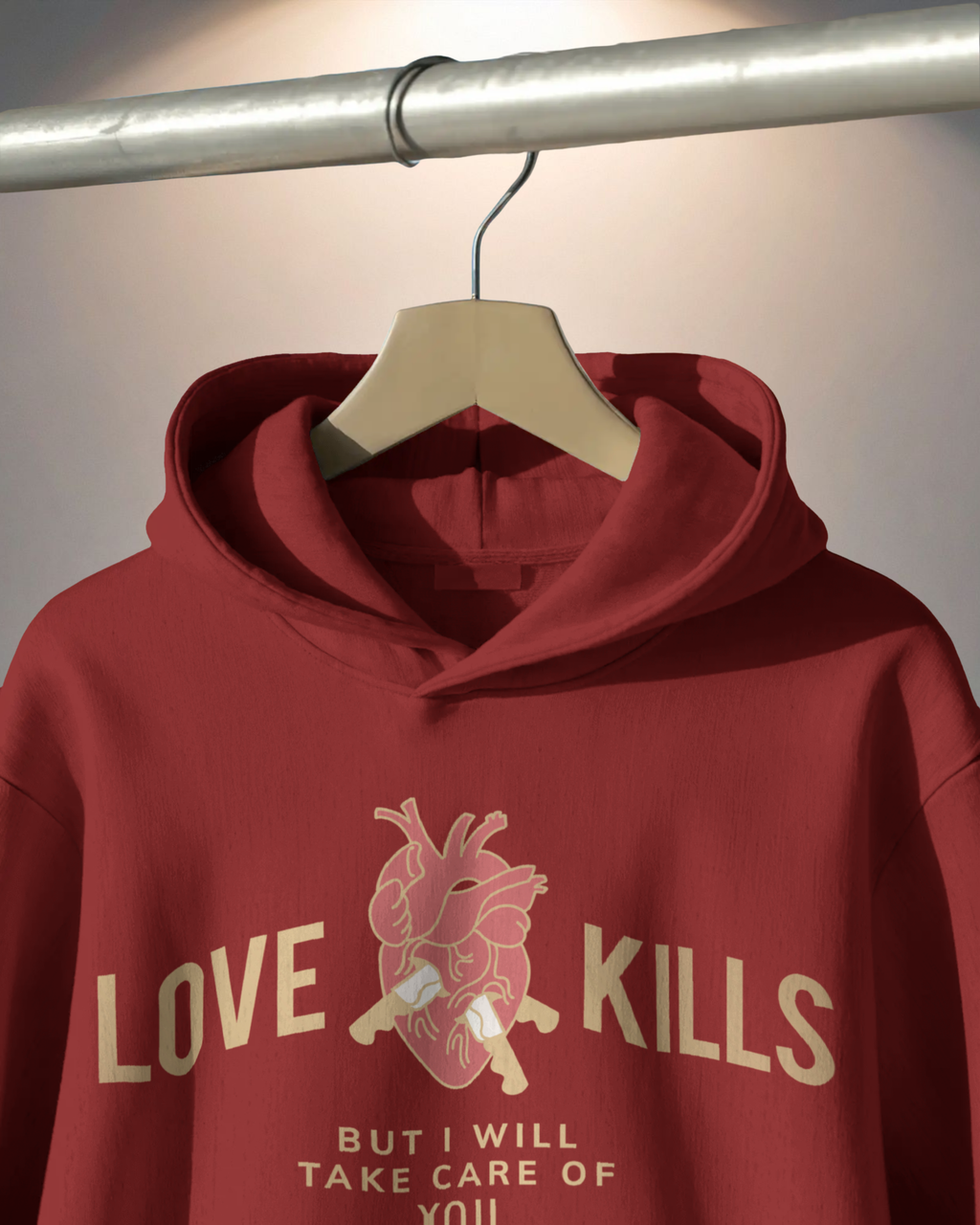 Red hoodie with graphic design and text on a hanger against a neutral background