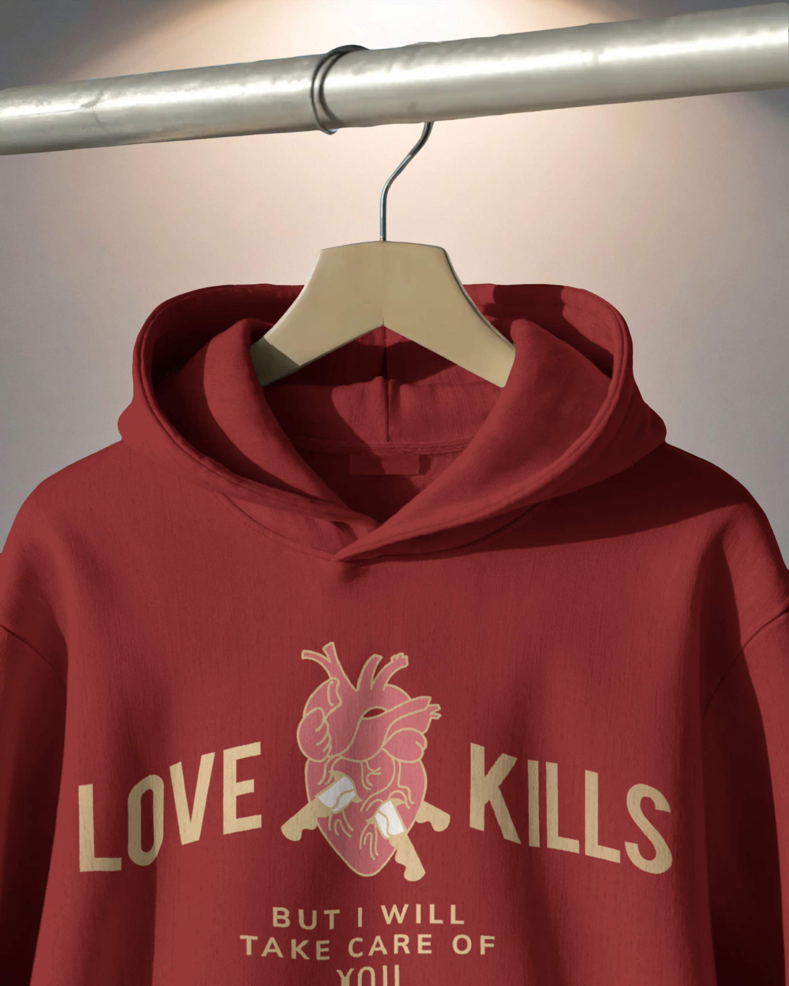 Red hoodie with graphic design and text on a hanger against a neutral background